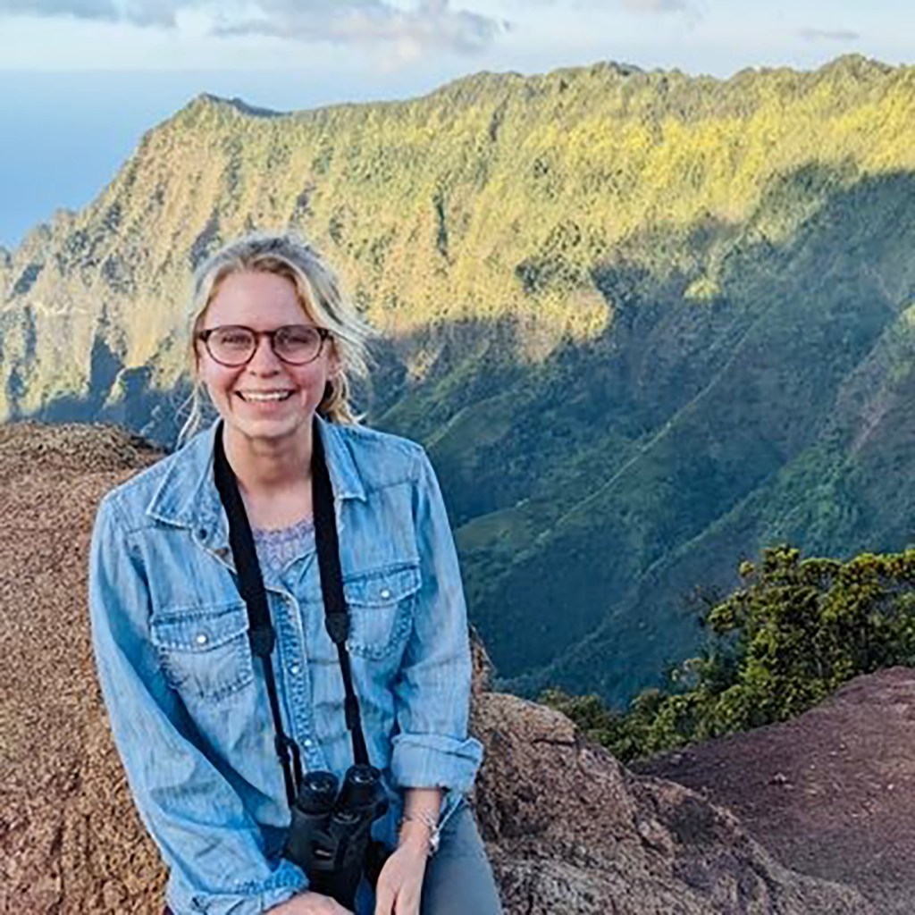 Caroline Kitchener sitting on a rock with binoculars facing a mountain, reporter for the Washington Post covering abortion issues